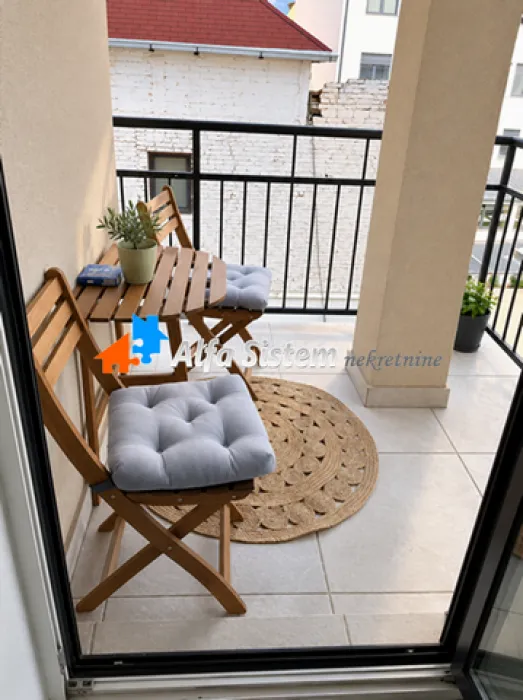 Small furnished balcony with a wooden table and chairs.