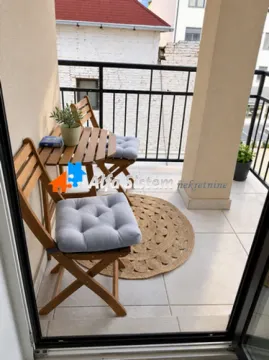 Small furnished balcony with a wooden table and chairs. - image 3