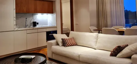 Dnevni boravak sa garniturom, trpezarijom i ugrađenom kuhinjom u pozadini. - image 9