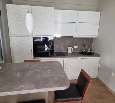 Modern kitchen with white cabinets, built-in oven, and a dining table. - image 4