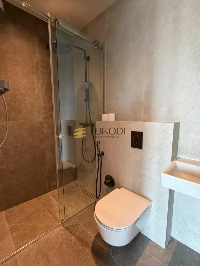 Savremeno opremljeno kupatilo sa tuš kabinom i ugradnom sanitarijom.