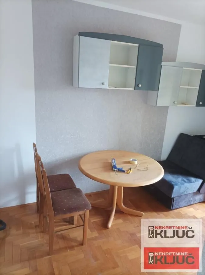 Manji dnevni boravak sa trpezarijskim stolom, stolicama i zidnim elementima.
