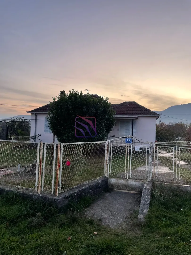 Pogled na dvorište i fasadu kuće sa ogradom u sumrak.