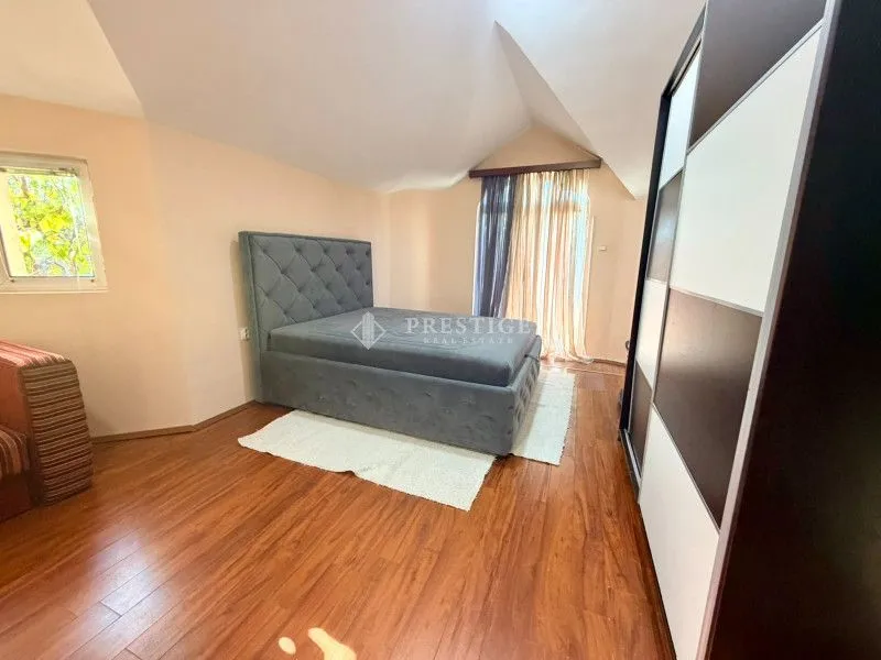 Attic bedroom with a double bed, wooden flooring, and a wardrobe.