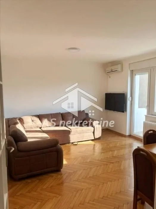 Living room with a corner sofa and parquet flooring.