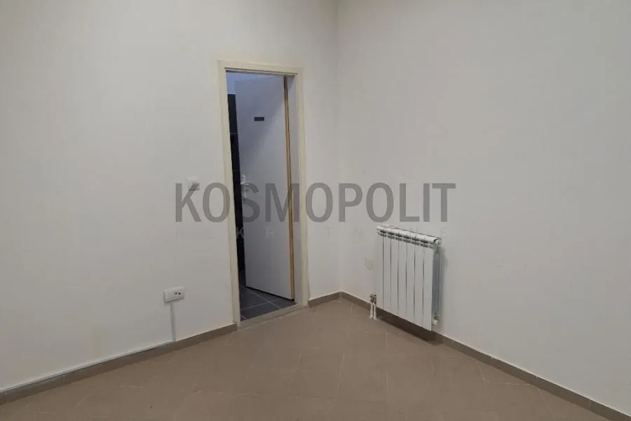 Empty room with light walls, tiled floors, and a radiator.