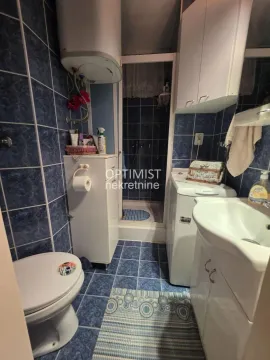 Manje kupatilo obloženo plavim pločicama sa tuš kabinom, umivaonikom i veš mašinom. - image 8