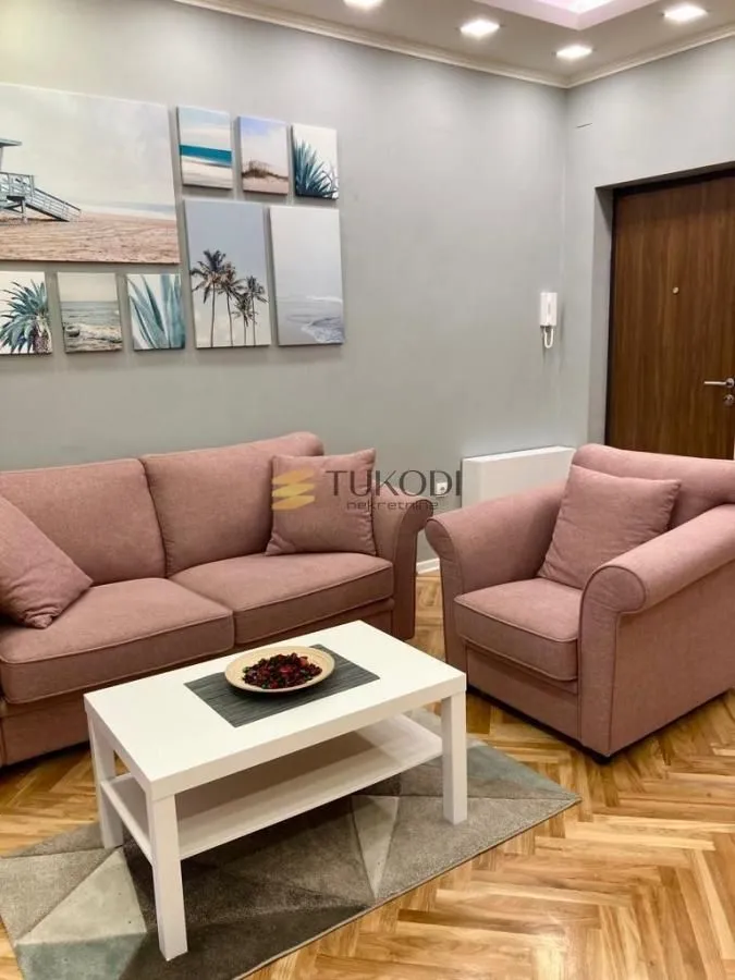 Living room with a pink sofa set, white coffee table, and wall art.