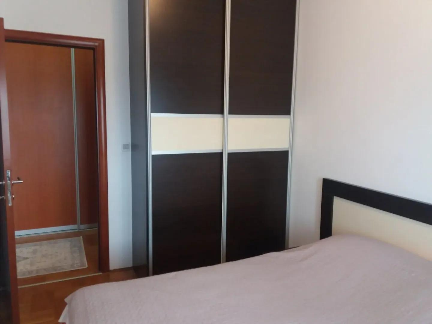 A bedroom featuring a large dark wardrobe and a bed.