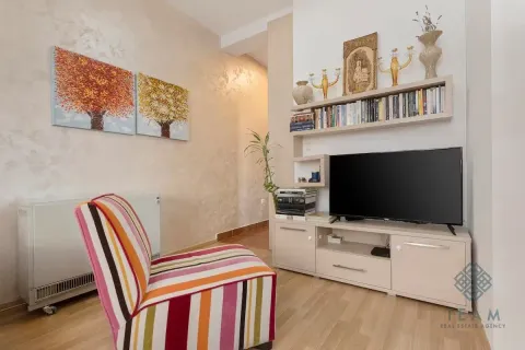 Living room with a colorful armchair, TV unit, and bookshelves. - image 3