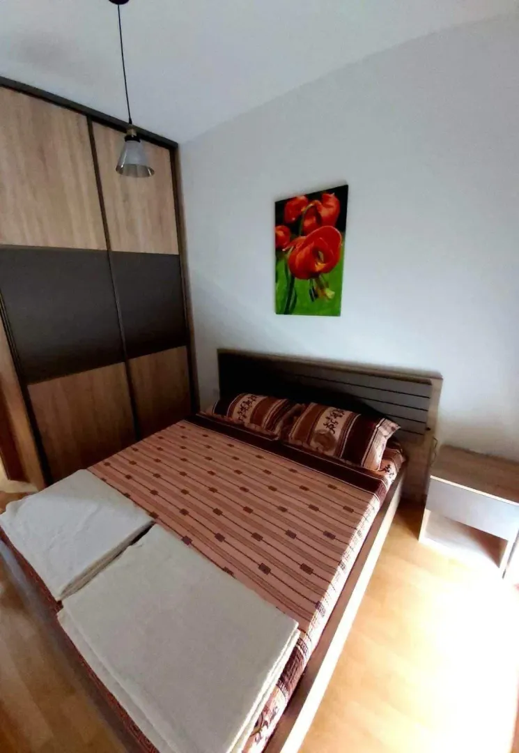 A bedroom featuring a double bed, a nightstand, and a large built-in wardrobe.