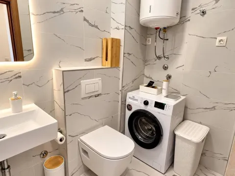 Modern bathroom equipped with a washing machine and shower. - image 8