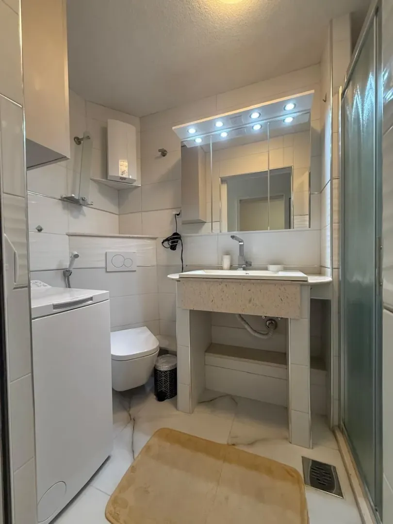 Kupatilo opremljeno umivaonikom, WC šoljom, tuš kabinom i mašinom za veš.