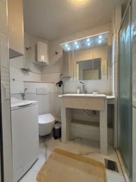 Kupatilo opremljeno umivaonikom, WC šoljom, tuš kabinom i mašinom za veš. - image 4