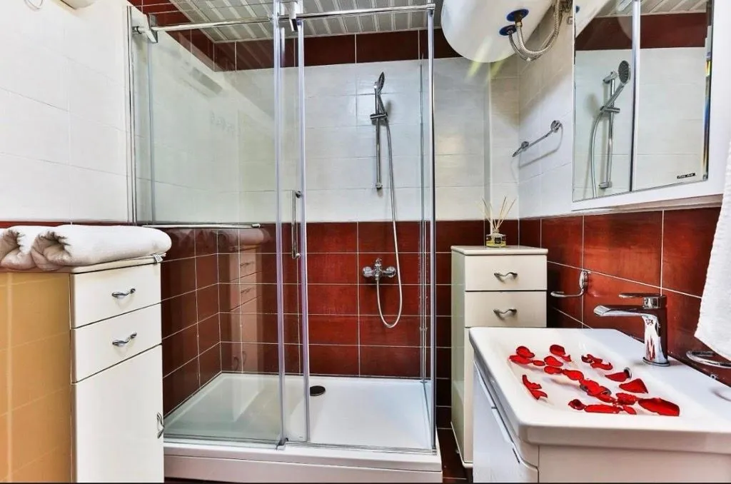 Bathroom with a shower cabin, washbasin, and white and red tiles.