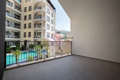 Nenamješten balkon sa pogledom na bazen i okolne zgrade.