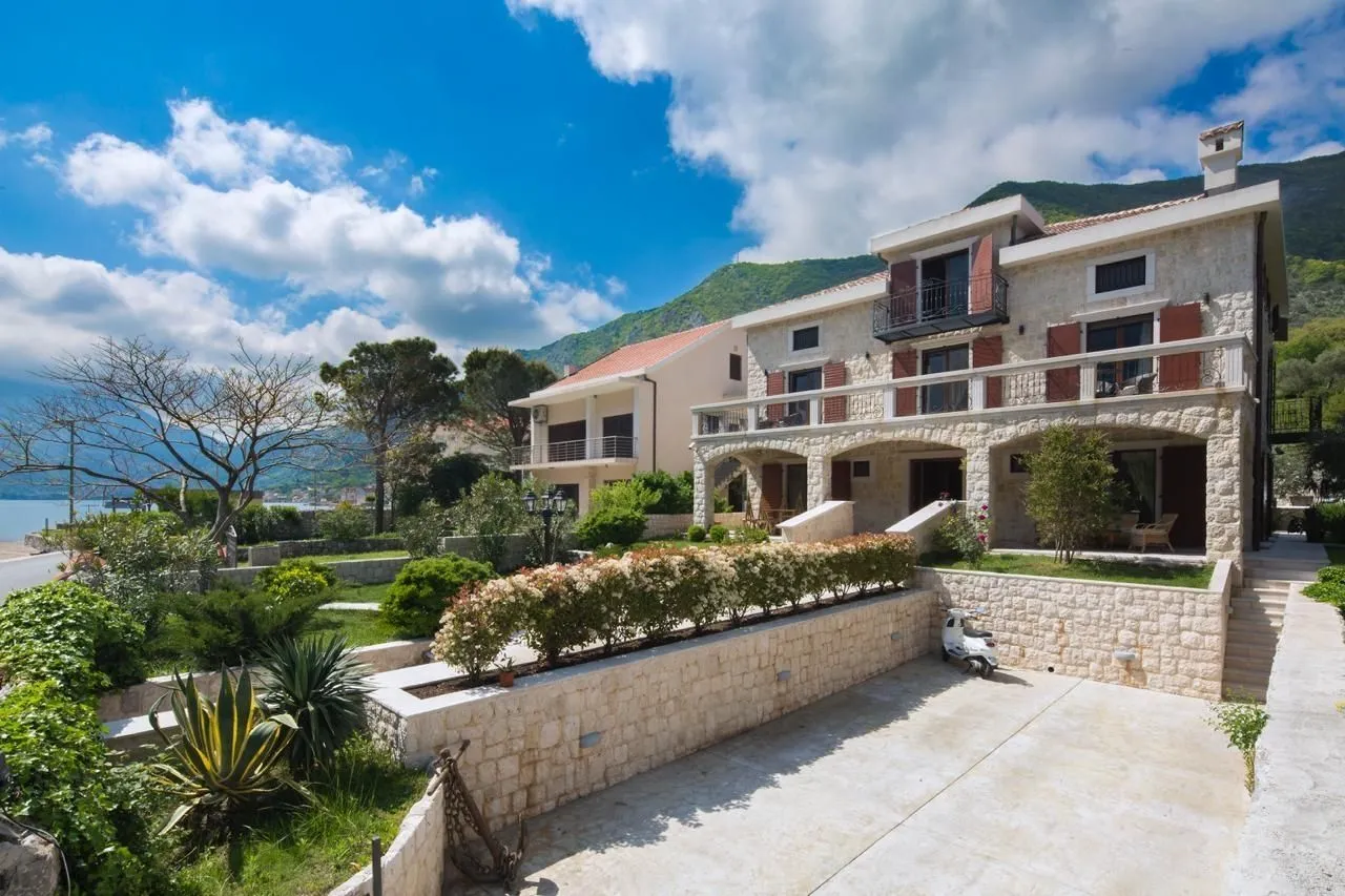 Stone house with a landscaped yard and parking near the sea.