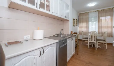 Kitchen equipped with white cabinets and a dishwasher, with a dining area in the background. - image 3
