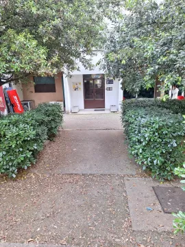 Entrance to a residential building surrounded by greenery and trees. - image 7