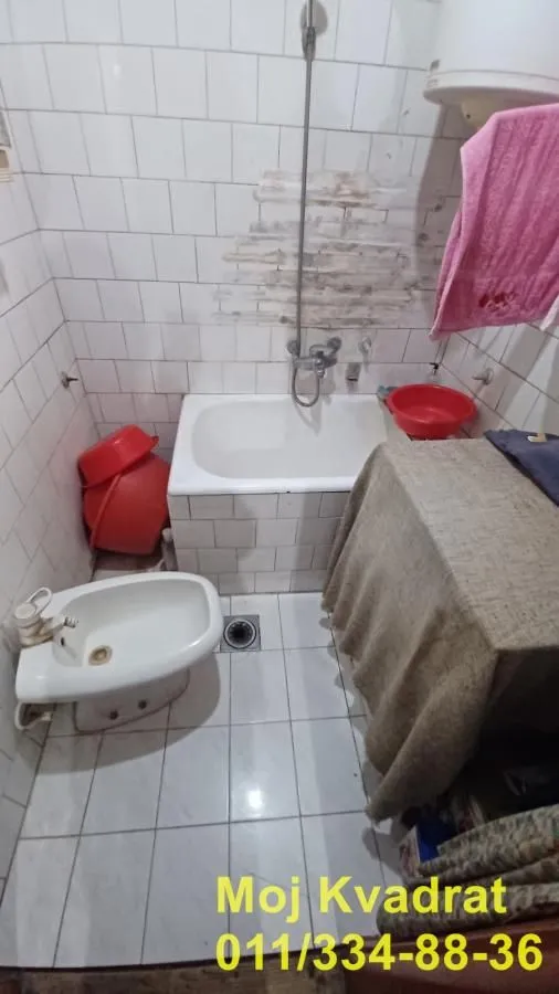 Starije opremljeno kupatilo sa kadom, bideom i pločicama na zidovima.