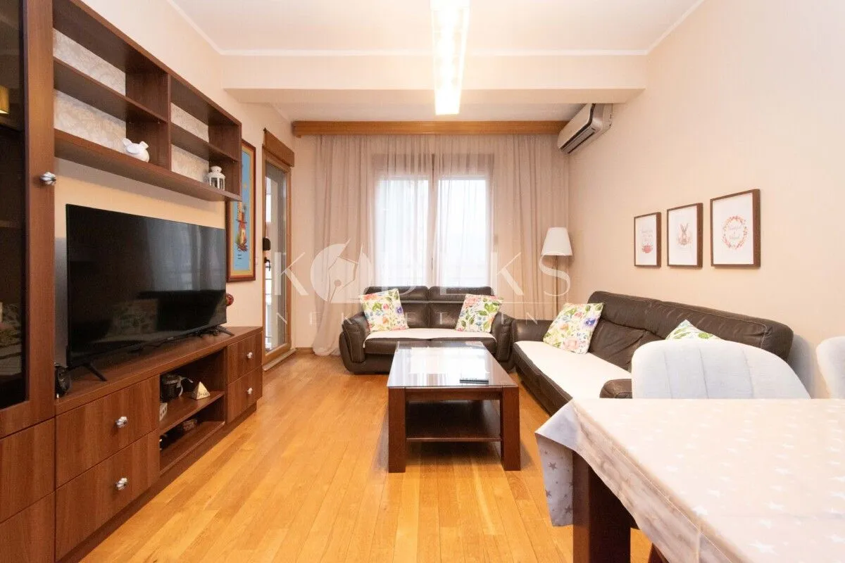 Living room with sofa set, TV unit and dining table.