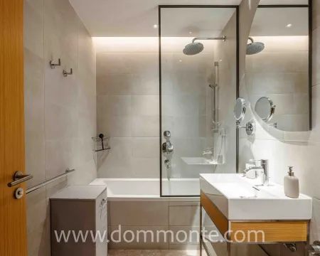 Modernly equipped bathroom with a bathtub, shower screen, and washbasin. - image 14