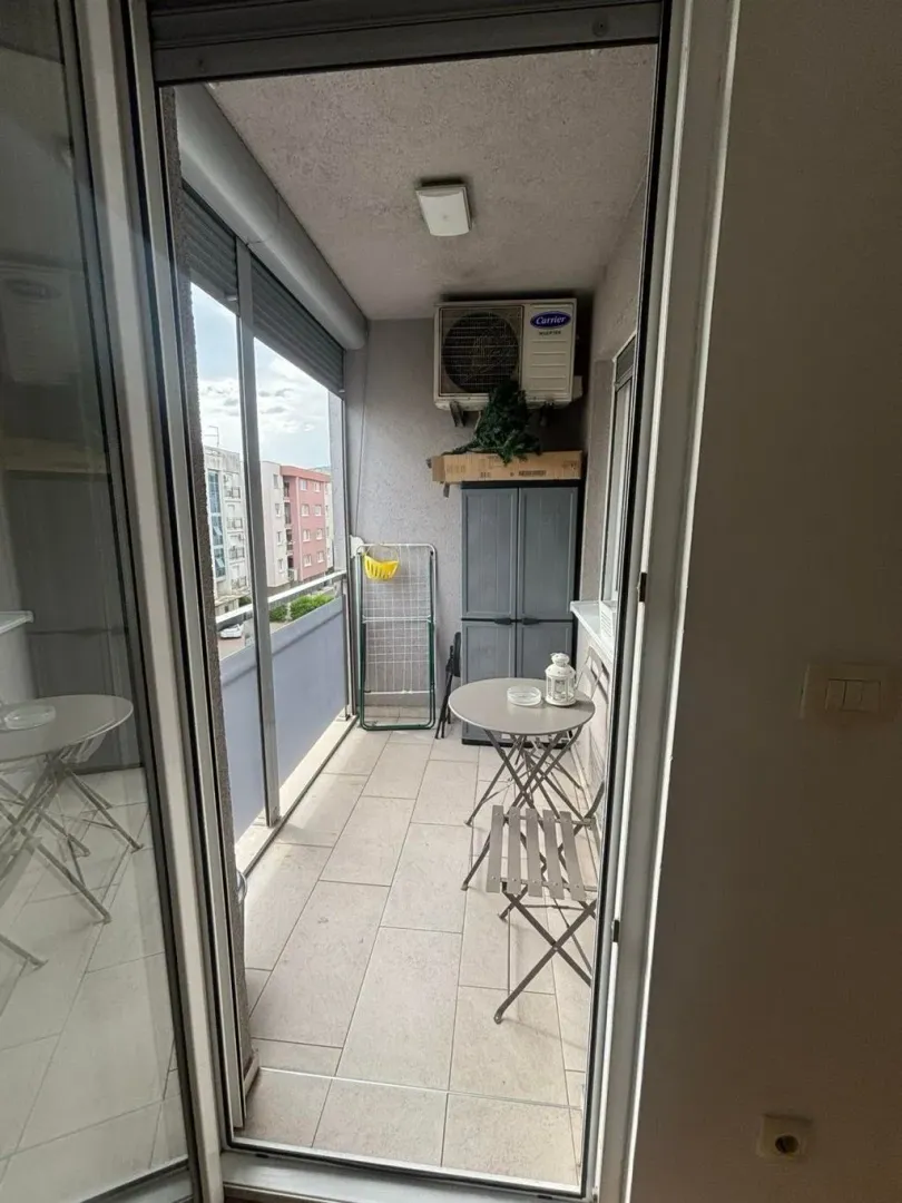 Smaller enclosed balcony with a table, chairs, and a cabinet.