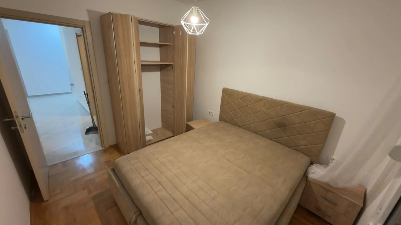 Namještena spavaća soba sa bračnim krevetom i ormarom.