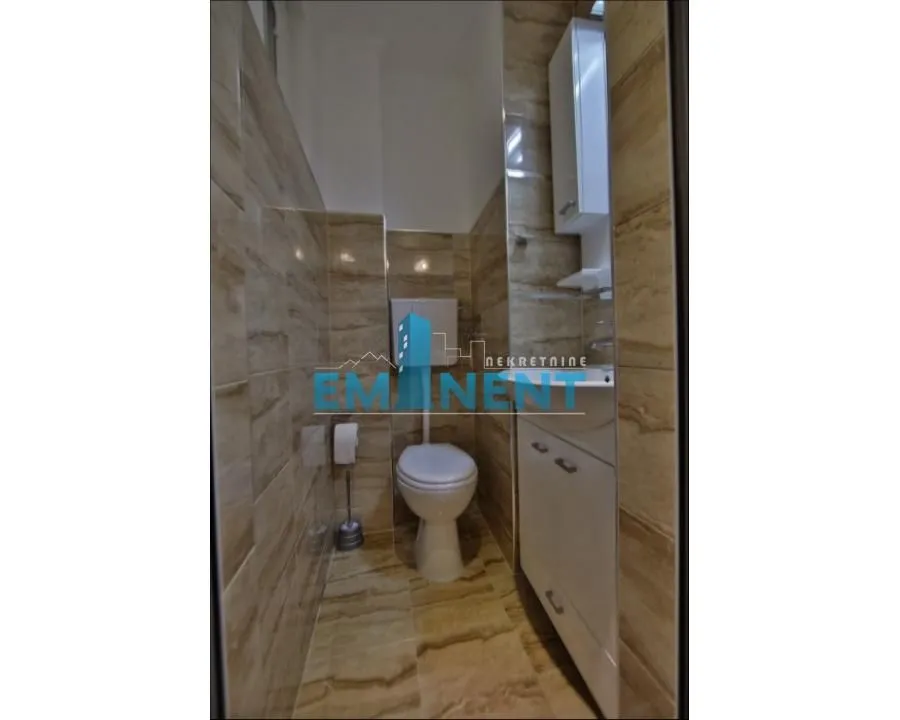 Manje kupatilo obloženo keramičkim pločicama sa WC šoljom i umivaonikom.