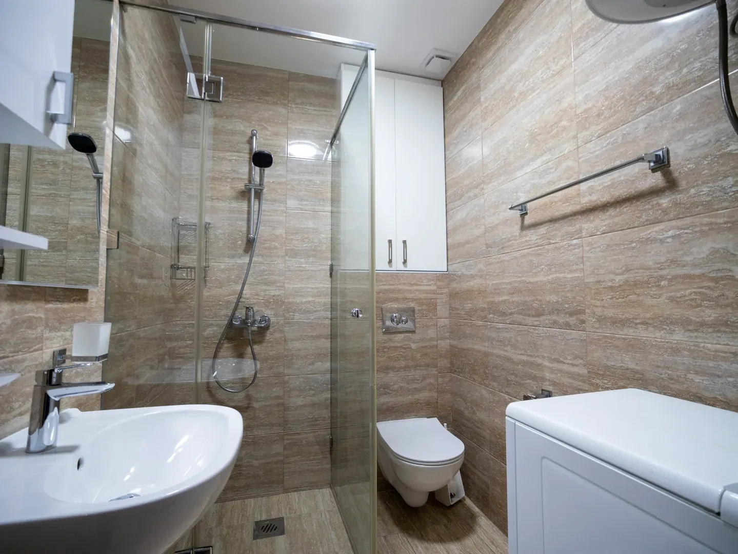 Moderne kupatilo sa tuš kabinom, umivaonikom i ugrađenom sanitarijom.