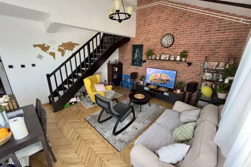 Dnevna soba sa garniturom, televizorom i stepeništem.
