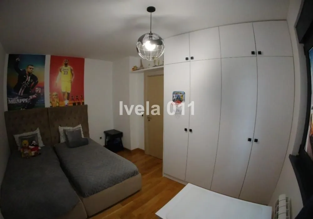 Dečja spavaća soba sa dva kreveta i velikim ugradnim ormarom.