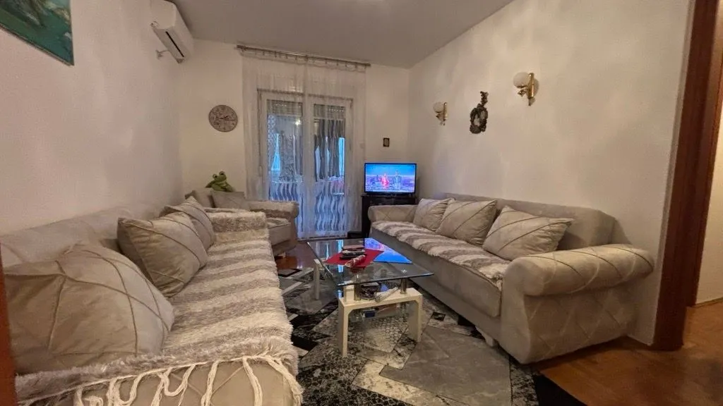 Dnevna soba sa garniturom, stočićem i televizorom.