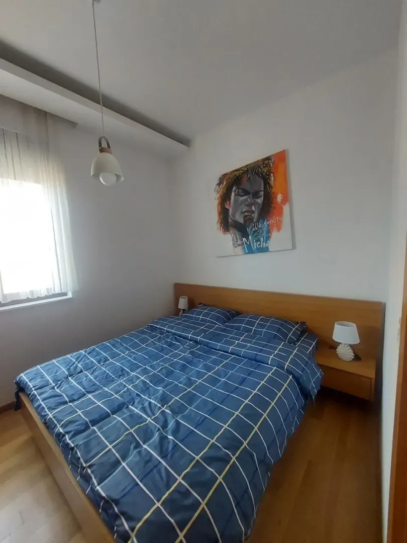 Tidy bedroom with a double bed, wooden flooring, and an artwork on the wall.
