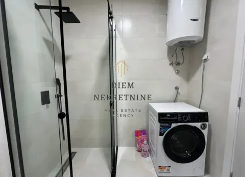 Modern bathroom with a walk-in shower, water heater, and washing machine. - image 11