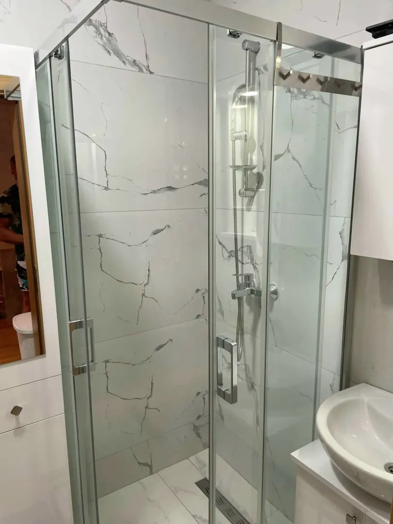 Modernly equipped bathroom with a shower cabin and white ceramic tiles.