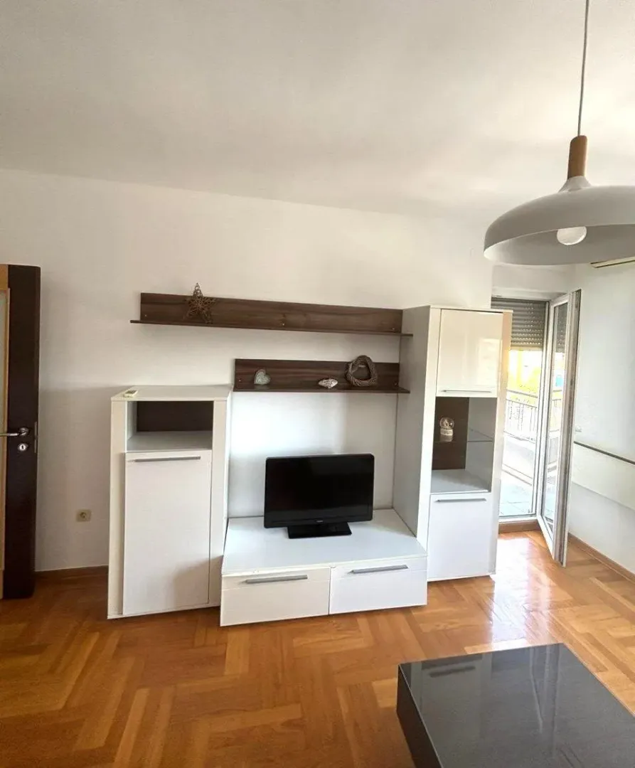 Living room with a white TV unit and wooden flooring.