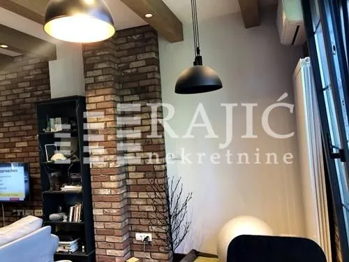 Living room with brick wall, modern pendant lights and bookcase.