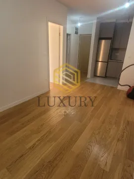 Living room with hardwood flooring and a view of the kitchen in the background. - image 2