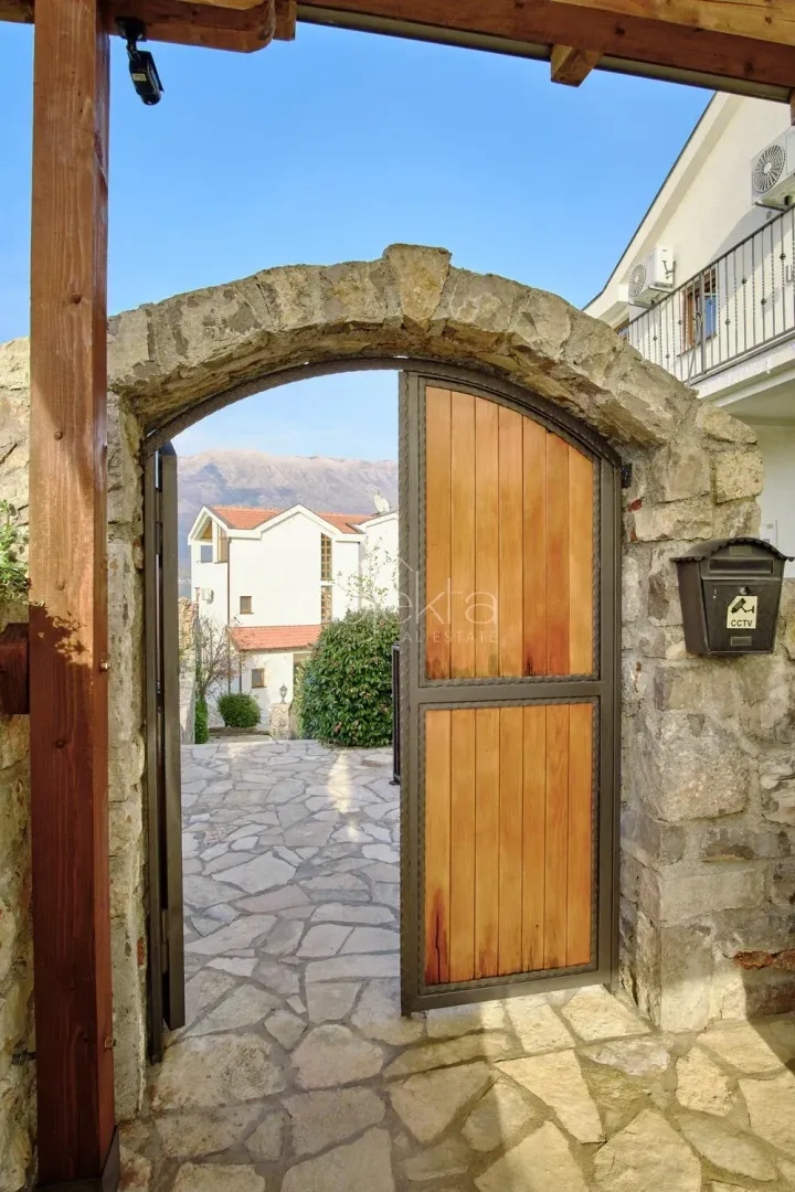 Stone-trimmed entrance with a wooden gate and paved courtyard.