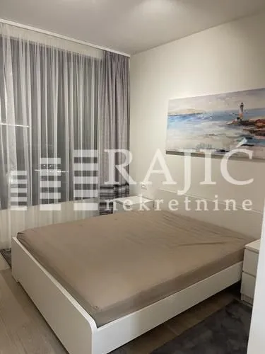 Nameštena spavaća soba sa bračnim krevetom, zavesama i slikom na zidu.