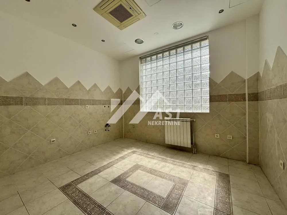 Empty room tiled with ceramic tiles and featuring a glass block window.