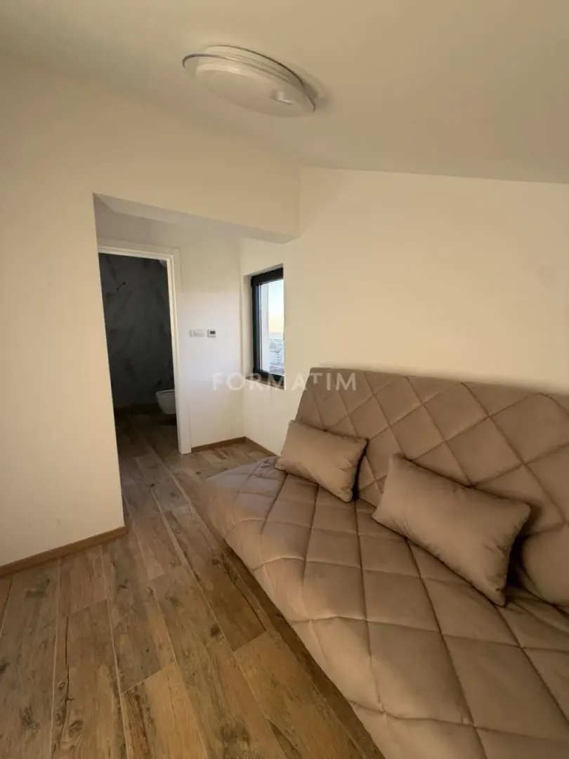 Living room with a sofa and a view towards the bathroom.