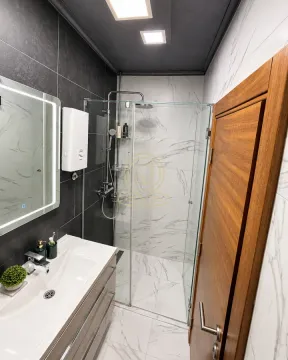 Savremeno opremljeno kupatilo sa tuš kabinom, umivaonikom i ogledalom sa osvetljenjem. - image 8