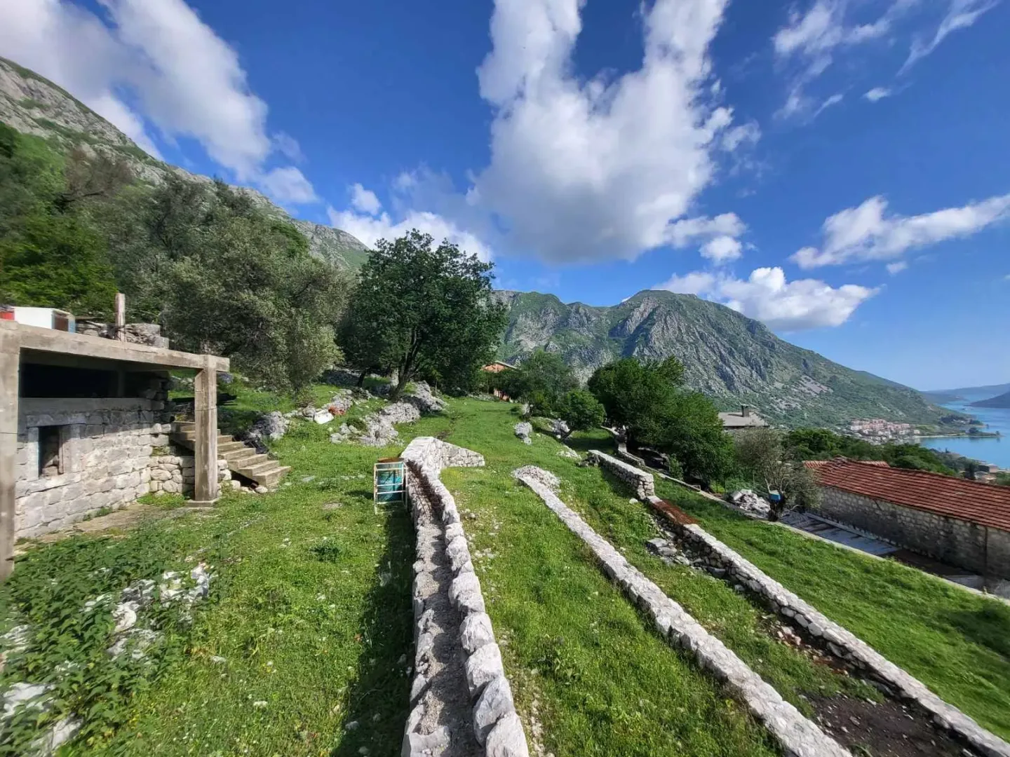 Pogled na zeleno dvorište sa terasastim vrtom i okolnim planinama.