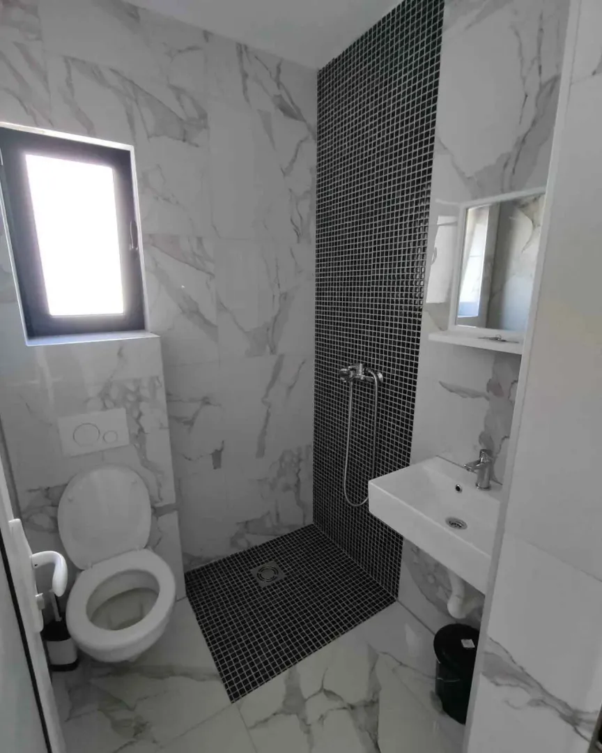 Savremeno opremljeno kupatilo sa tuš kabinom, umivaonikom i WC šoljom.