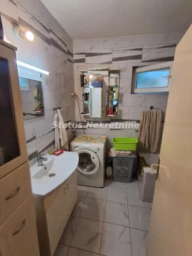 Kupatilo opremljeno umivaonikom, veš mašinom i elementima za odlaganje. - image 8