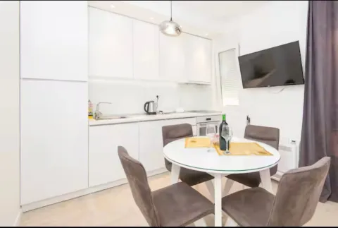 Modern white kitchen with a dining table and chairs. - image 3