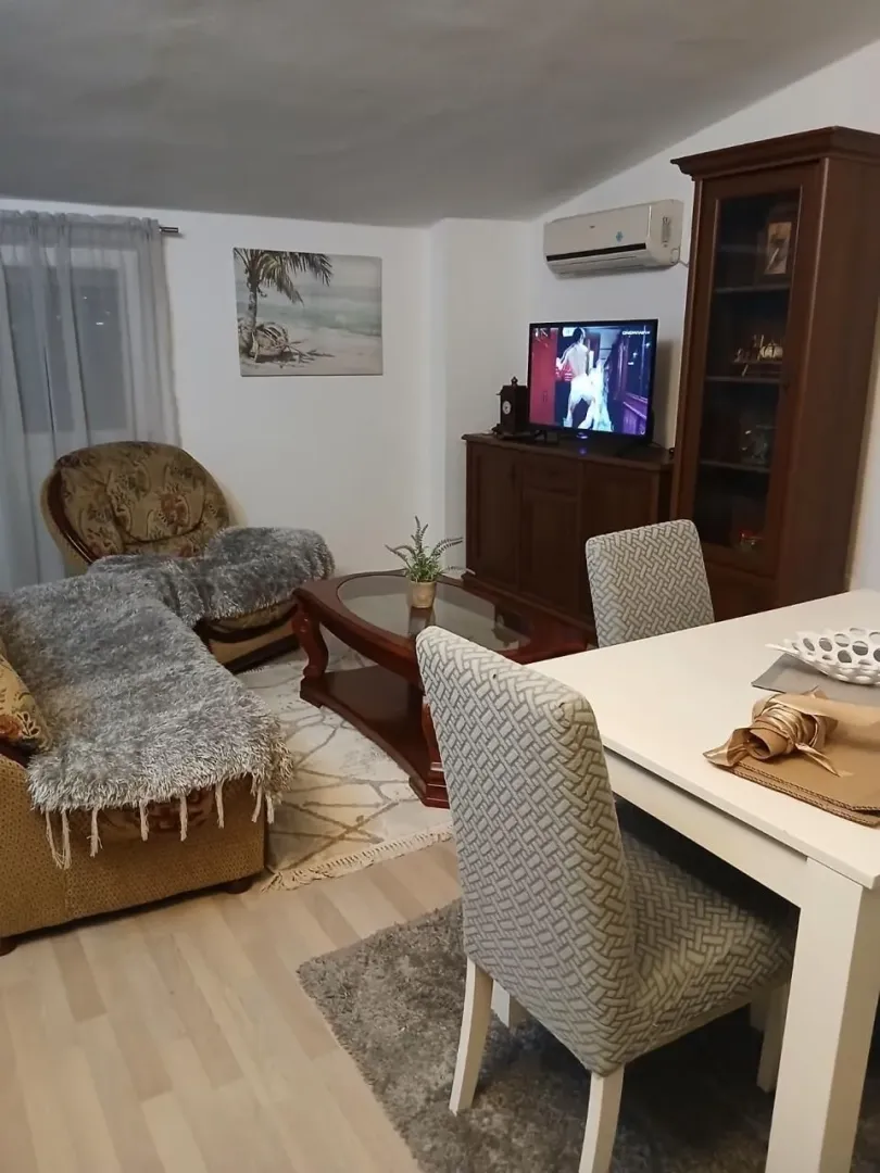 Dnevna soba sa garniturom, trpezarijskim stolom i TV komodom.
