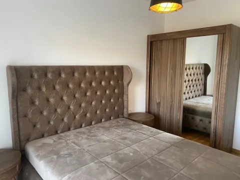 Modern bedroom featuring a large upholstered bed and a wooden wardrobe with a mirror. - image 4